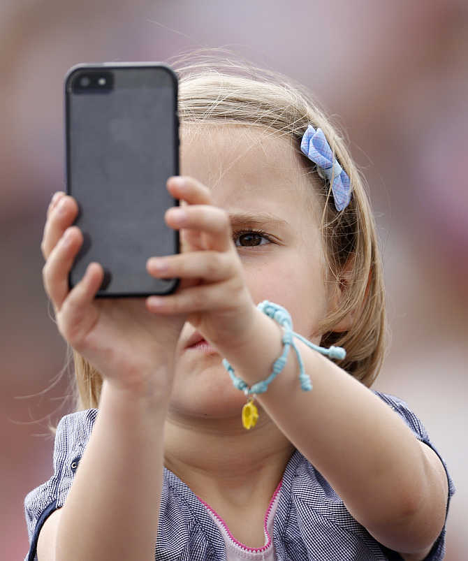 A child takes pictures with a mobile phone as Pope Francis leads the Angelus prayer from a window of the Apostolic Palace in Saint Peter's Square at the Vatican.
