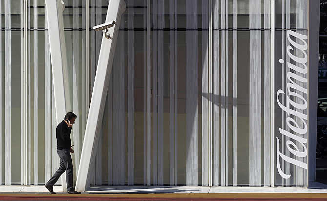 A man speaks on a mobile phone next to Telefonica's tower in Barcelona, Spain.