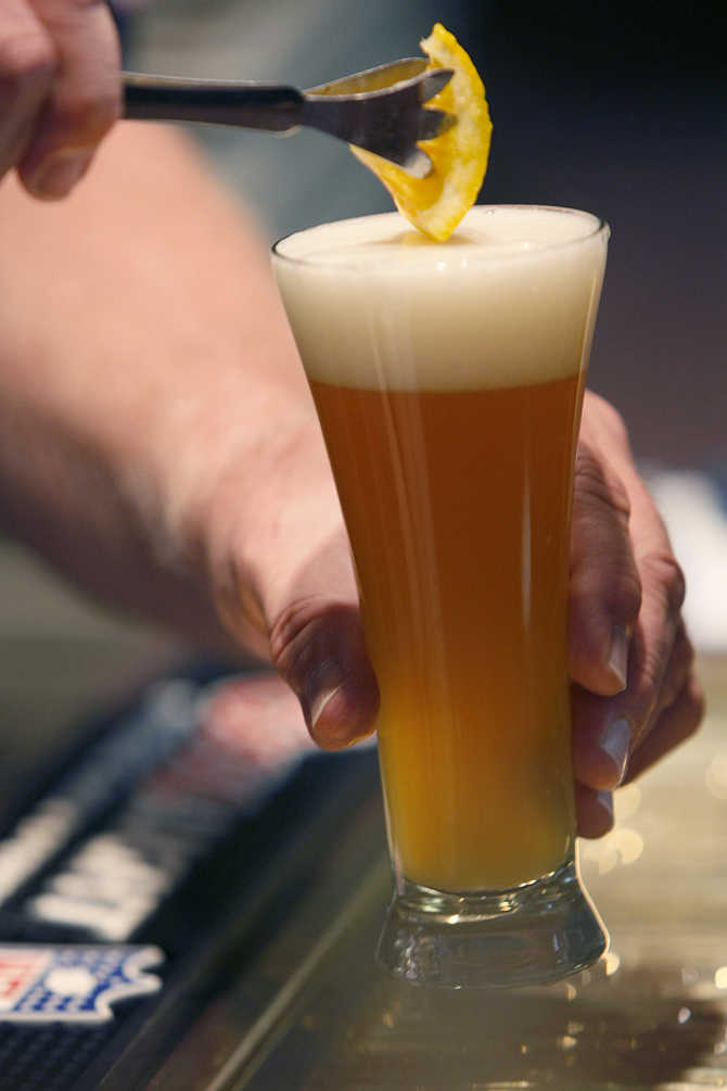A bartender adds a slice of orange to a Blue Moon Ale for a tourist in Golden, Colorado.