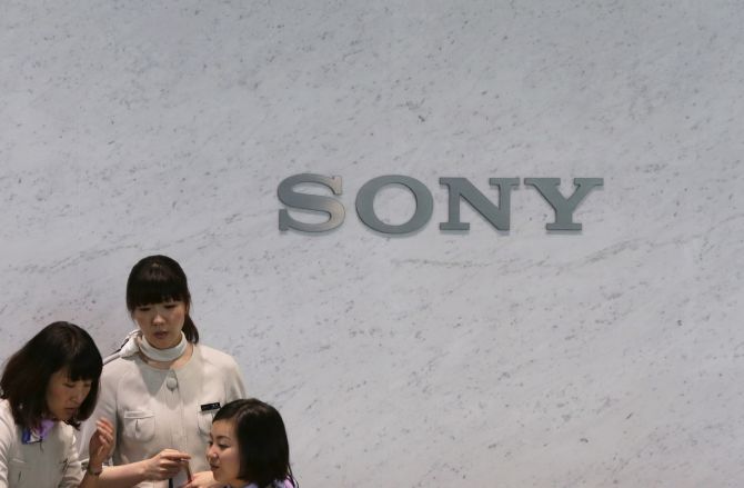 Receptionists of Sony Corp are seen in front of the company's logo at the headquarters in Tokyo.