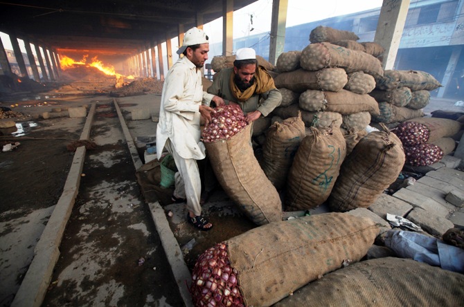 Men try to move sacks of onions to a safer place after a fire in a wholesale vegetable and fruit market.