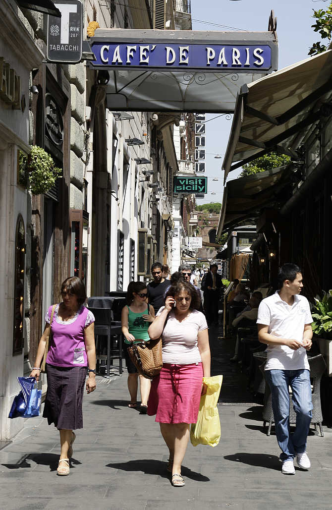 Shoppers walk past the Cafe De Paris on Via Veneto in Rome, Italy.