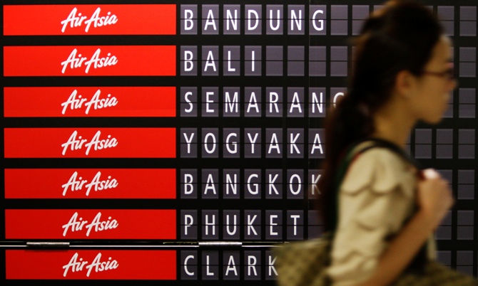 A commuter passes an AirAsia advertisement showing the destinations that the budget carrier flies to, at a train station in Singapore.