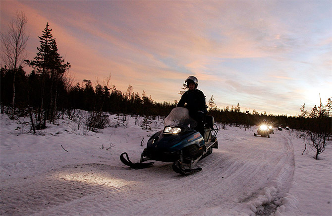 Tourists drive snowmobiles during an arctic safari at Arctic Circle near Rovaniemi, northern Finland.
