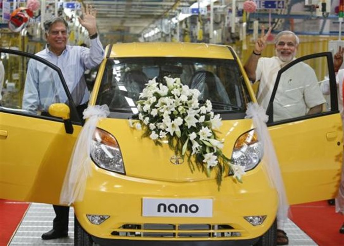 Ratan Tata (L), chairman of the Tata Group, and Gujarat's chief minister Narendra Modi wave as they stand beside the Tata Nano car during the inauguration ceremony of a new plant for the Tata Nano at Sanand in Gujarat 