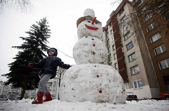 A child plays with a snowman after a snowfall in central Bosnian town of Zenica.