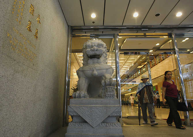 Customers walk out of Wing Lung Bank headquarters in Hong Kong.