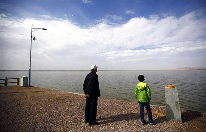 Visitors look at the Hongyashan water reservoir on the outskirts of Minqin town, Gansu province.