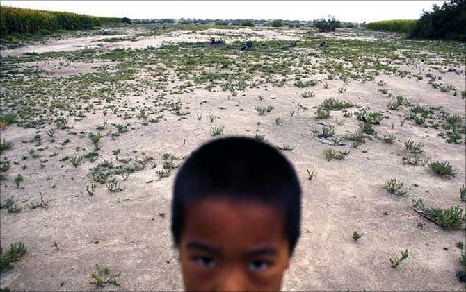 A child stands in a field near the dried up Shiyang river on the outskirts of Minqin town, Gansu province.