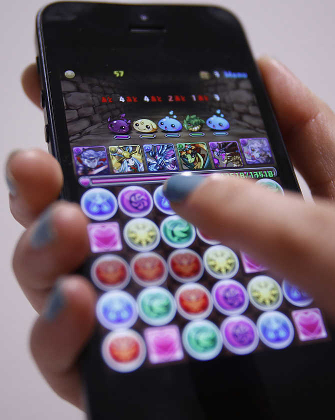 A user plays a mobile game on her iPhone in Tokyo, Japan.