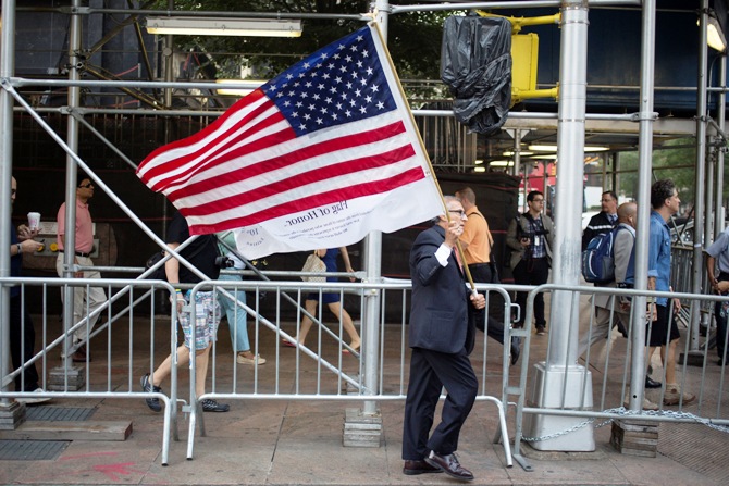 A man walks with a U.S. flag before a moment of silence honoring the victims of the September11 attacks outside the World Trade Center site in New York.