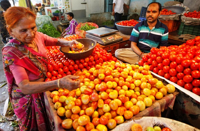 A woman buys tomatoes at a wholesale vegetable market.