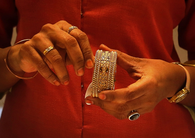 An employee shows a gold bangle to a customer inside a jewellery showroom in Mumbai.