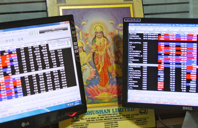 An image of Lakshmi, the Hindu goddess of wealth and prosperity, is placed between monitors displaying share price index at a share trading market in Chandigarh.