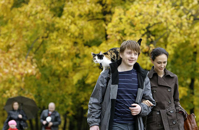 A couple walk with a cat in Kolomenskoye Park in Moscow, Russia.