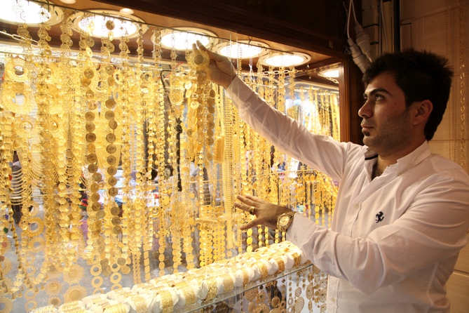 A goldsmith shop owner displays gold pieces at a gold market.