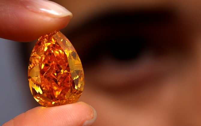 A Christie's member of staff displays 'The Orange', the world biggest orange diamond, which weighs 14.82 carats during an auction preview.