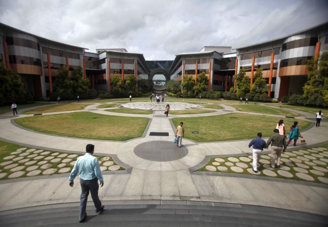Employees walk in a forecourt at the Infosys campus in the Electronic City area of Bangalore.
