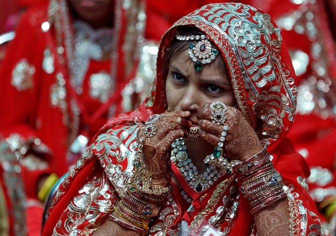 A bride adjusts her nose ring before taking her wedding wows during a mass marriage ceremony in Ahmedabad.