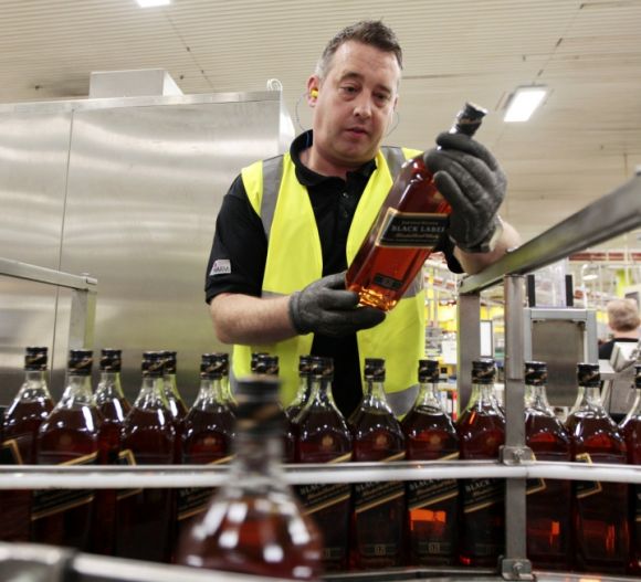 A worker looks at bottles of Johnnie Walker whisky on the production line at the Diageo owned Shieldhall bottling plant in Glasgow, Scotland.