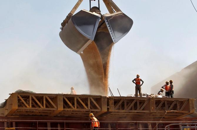 Workers stand as a crane loads wheat onto a ship at Mundra Port in Gujarat.