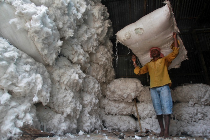 A worker carries a sack filled with cotton at a wholesale cotton market in Agartala.