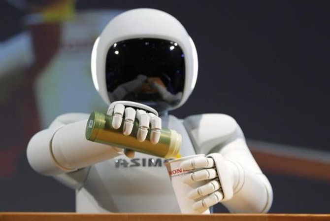 Asimo pours a drink into a cup during a news conference at the 42nd Tokyo Motor Show in Tokyo.