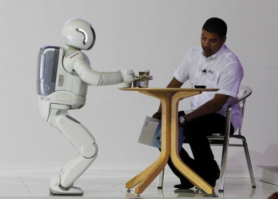 Asimo serves tea to a visitor during the Johannesburg International Motor Show at Nasrec in Johannesburg.