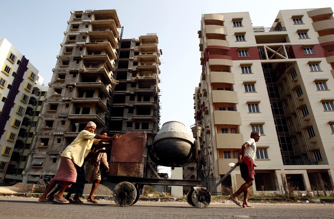 Labourers move a concrete mixer past under construction site of residential buildings in Kolkata.