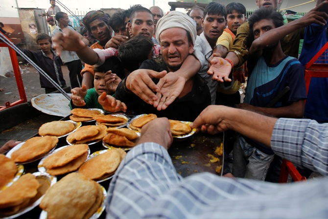 People reach out their hands as they wait to receive food provided by a charitable organisation outside a temple in New Delhi.