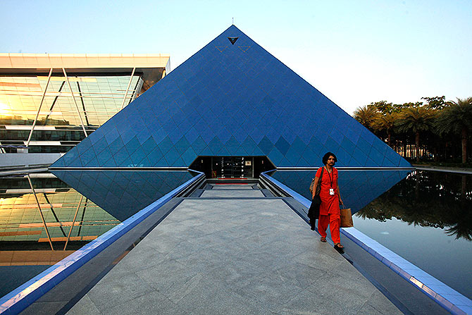 n employee walks out of an iconic pyramid-shaped building made out of glass in the Infosys campus.
