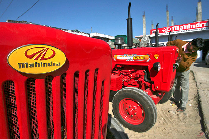 A worker cleans a Mahindra tractor outside its showroom on the outskirts of Jammu.