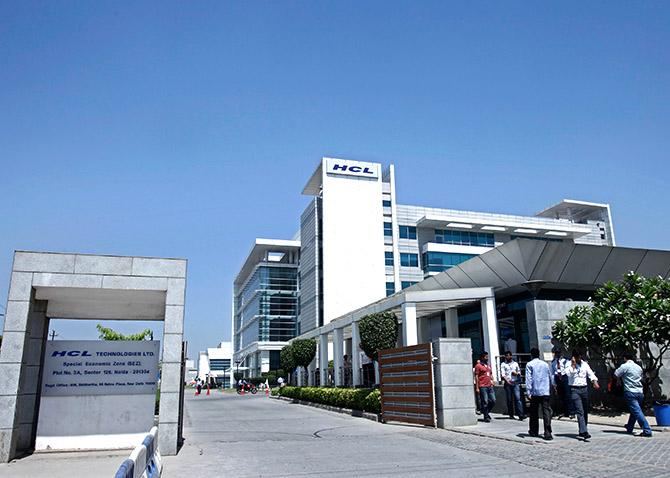 People walk in front of the HCL Technologies Ltd office at Noida, on the outskirts of New Delhi.