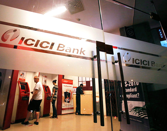 Customers use ATM machines at an ICICI Bank branch in Mumbai.