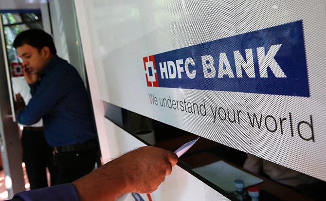 A customer walks out of a HDFC Bank branch as another deposits a cheque at a counter in Mumbai.