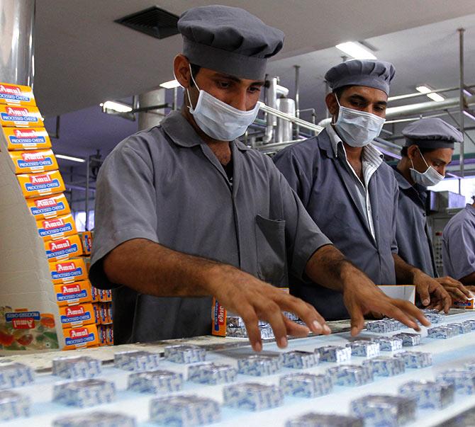 Workers pack processed cheese cubes during a media tour to Amul satellite dairy in Khatraj village.