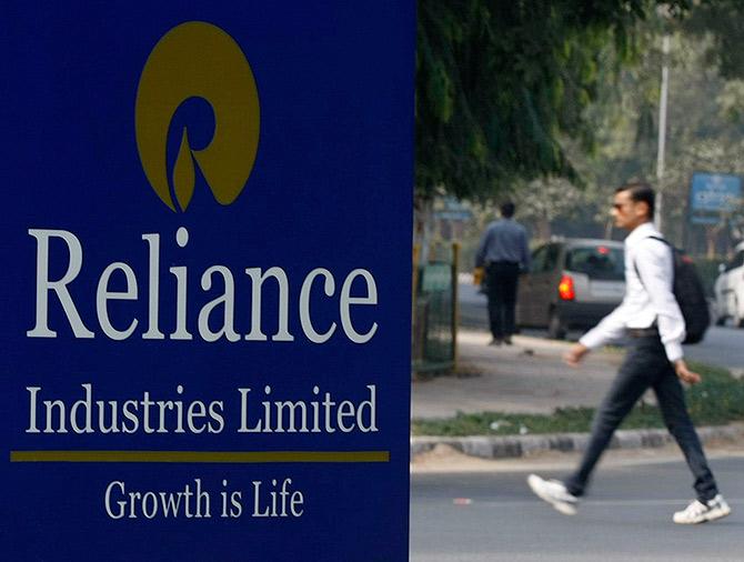 A man walks past a Reliance Industries Limited sign board installed on a road divider in the western Indian city of Gandhinagar.