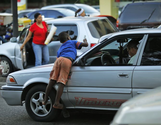 An immigrant child from Haiti cleans the windshield of a car before asking for money on the streets of Santo Domingo.