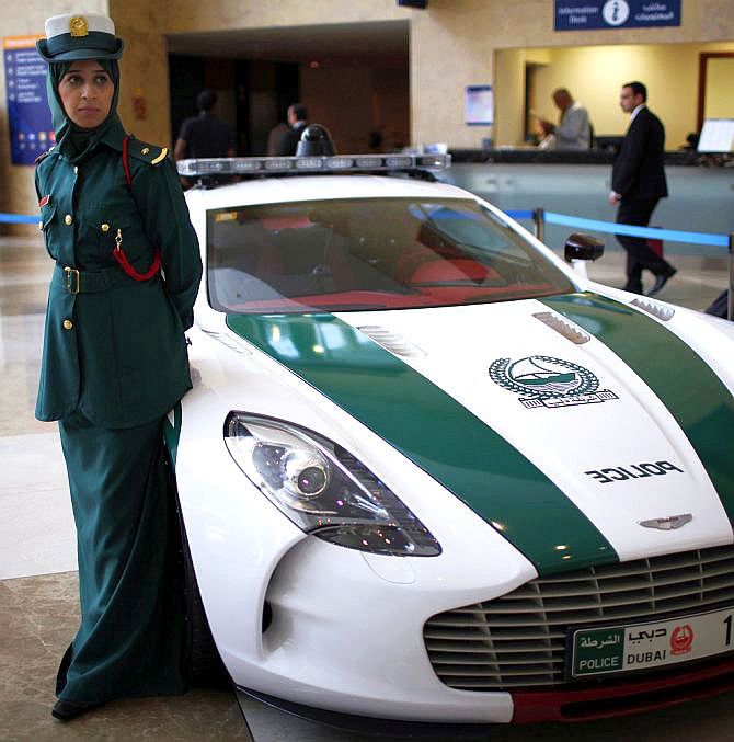 A police officer stands near an Aston Martin car used by Dubai police.