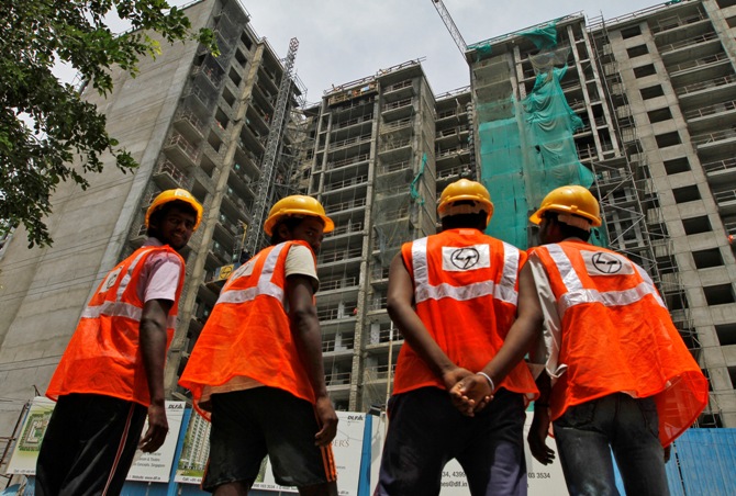 Construction workers stand in front of a residential building under construction in Chennai.