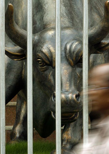 A man walks past a bronze statue of a bull outside the Bombay Stock Exchange.