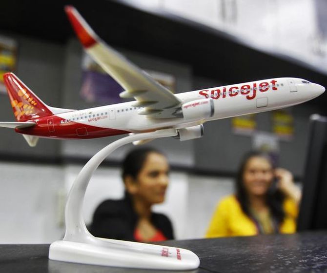 Employees work inside a travel agency office besides a model of a SpiceJet aircraft.