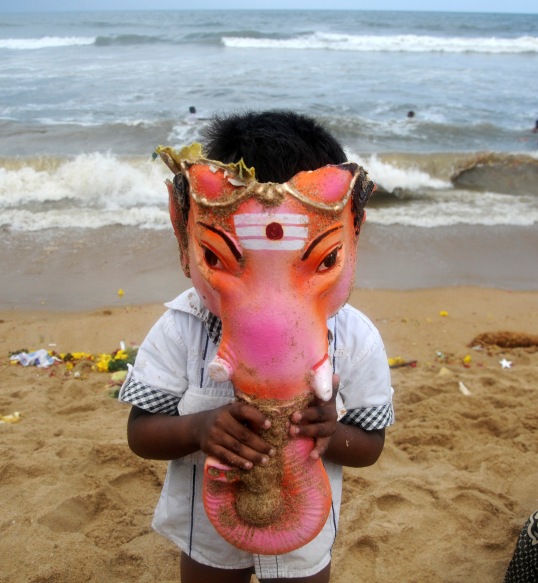 A boy wears the head of an idol of Ganesh, deity of prosperity, during immersion of the 10-day-Ganesh Chaturthi, in Chennai September 15, 2013.