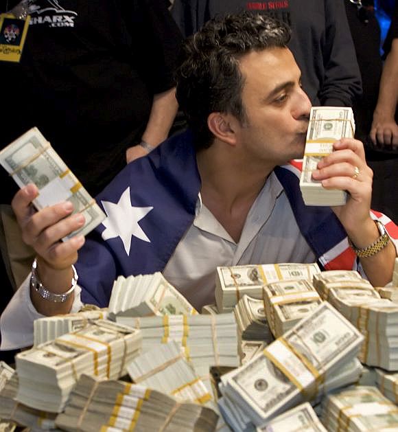 Joseph Hachem kisses a stack of $100 bills after winning World Series of Poker.