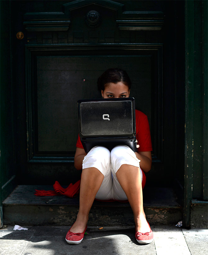 A girl wearing the traditional red and white festival costume uses a laptop computer.