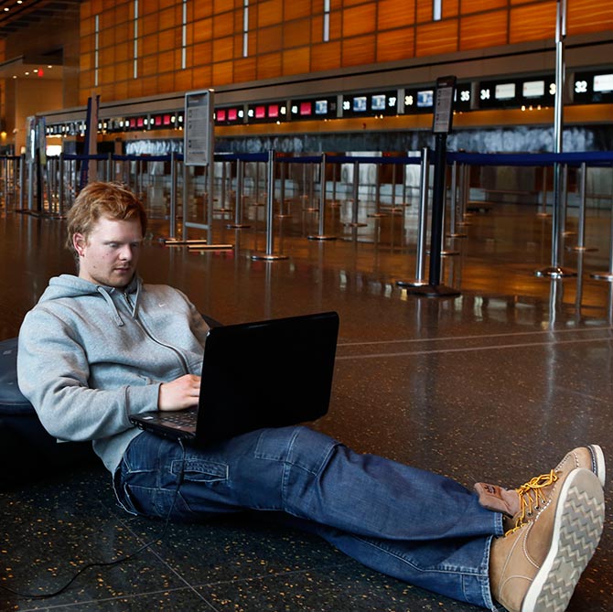 Rasmus Thomsen of Denmark works on his computer as he waits at Boston Logan International Airport.