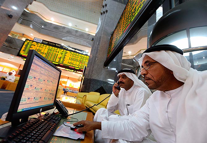 Investors monitor screens displaying stock information at the Abu Dhabi Securities Exchange.
