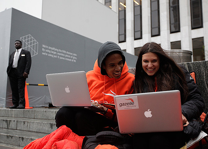 Keenen Thompson and Jessica Mellow (R) surf the web while waiting in line to buy an iPhone 4S at the Apple Store.