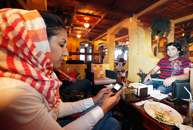 A woman checks her messages on her mobile phone at a coffeeshop.