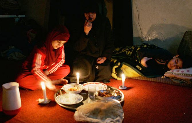 Iraqi migrant Ahlam al-Jibouri and her children eat a meal during a power outage.